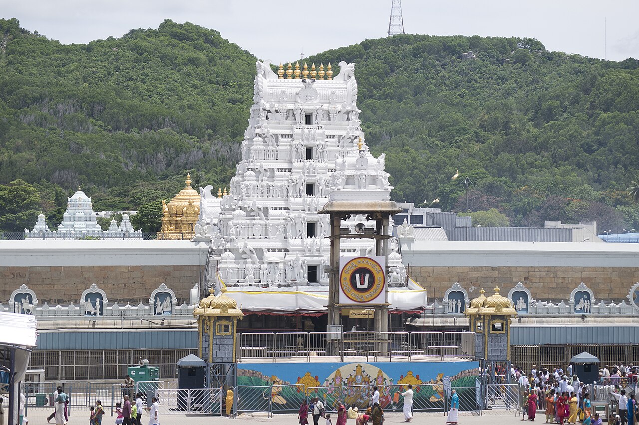 White entrance gopuram of Sri Venkateswara Swamy Temple at Tirumala, with the golden vimana and hills behind